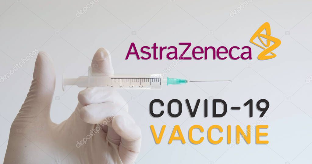 Hand with glove holds syringe next to AstraZeneca logo, one of the companies developing a Covid-19 (Coronavirus) vaccine. Vienna, Austria - January 18, 2021