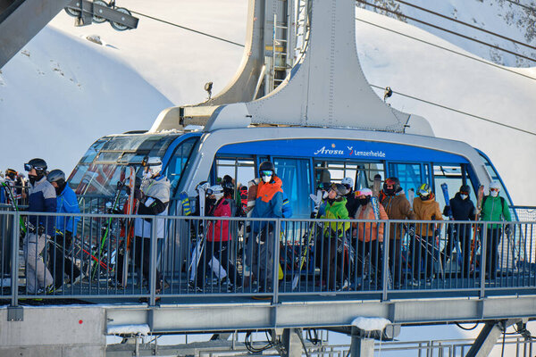 Skiers with medical masks exit the Urdenbahn cable car at the Arosa Lenzerheide ski resort, part of Covid-19 regulations for the Winter season. Switzerland - March 24, 2021.