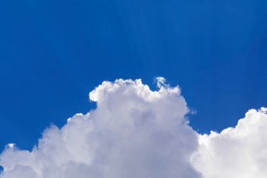 Mavi gökyüzünde dramatik beyaz bulutlar süzülür.