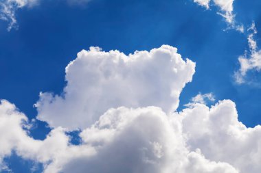 Mavi gökyüzünde dramatik beyaz bulutlar süzülür.