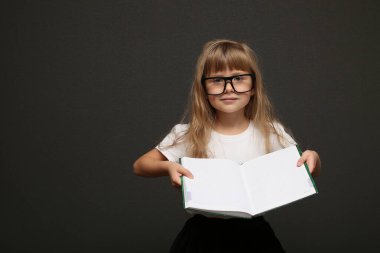 Akıllı kız güzel gülümseyen gözlüklü sevimli çocuk elinde bir kitapla içeriğini gösteriyor.