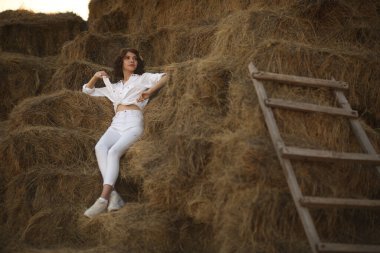 Kırsal tarzda hasır şapkalı genç ve güzel bir kız elinde hasır bir sepetle kırsalda, eski bir ahşap merdivende dinleniyor. Tatil İzolasyon Yazı