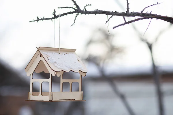 Drewniany pusty domek z zabawek wiszący na drzewie zimą. Ptasie żarcie, nowy dom. Pomoc w żywieniu zwierząt. — Zdjęcie stockowe