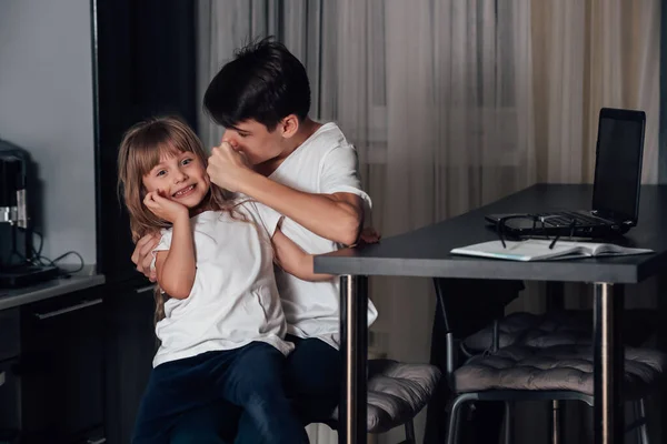 teenager boy older brother offends little sister girl. Angry and screaming, furious. Raised his fist on the girls hands, wanting to hit or hit. Both are at home in the living room.