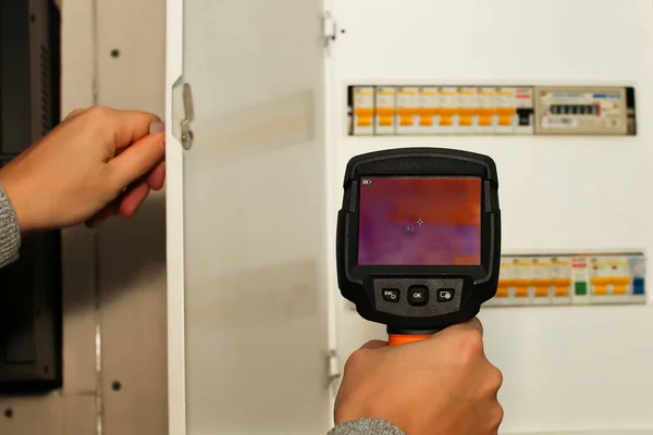 Az elektromos berendezések hőképalkotó vizsgálata. Közelkép férfi kézi felvétel hőveszteség infravörös termikus fényképezőgép — Stock Fotó