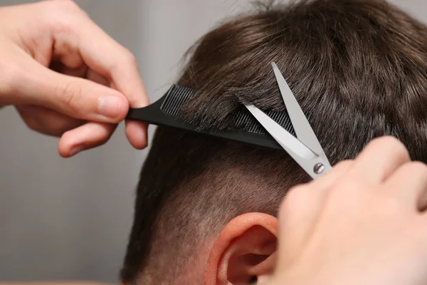 Detailní záběr na ruce držet nůžky a hřeben při stříhání vlasů muže. Holičství. Hnědé vlasy jsou krátké. — Stock fotografie