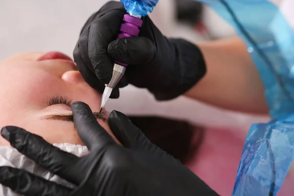 permanent eyebrow makeup in the salon. Close-up. Sterile, gloves, tattoo machine.