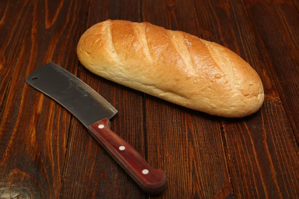 Pan blanco pan casero caliente rústico apetitoso sabroso en el horno en una tabla de cortar sobre un fondo de madera — Foto de Stock