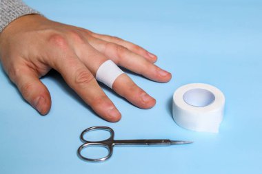 Kesikler ve parmaklarda yaralanmalar için ilk yardım. Yaralı bir erkek eli. Antiseptik, yapıştırıcı sıva, makas..