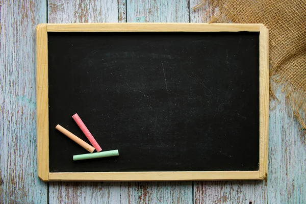 Empty chalk board with copy space on a painted wooden background. Colored chalk. Background for notes. Information board.