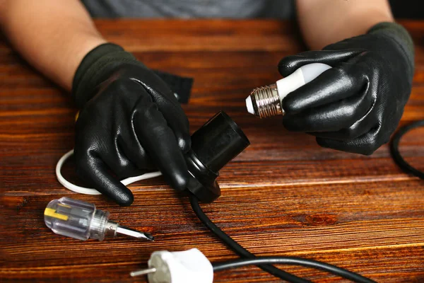 Homme fixer des fils de lampe de bureau vue de dessus. Électricien réparer les lumières. Technicien concept de lieu de travail de service. Outils et instruments sur table. Mains masculines tenant des pièces électroniques cassées, détails — Photo