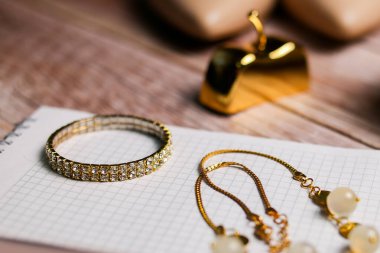 The gold bracelet lies on a blank notebook. To-do list for the bride, goals, wedding schedule.