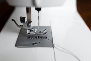 Dikiş makinesi. Kancaya yakın çekim ve ayaklar dikiş makinesinde.