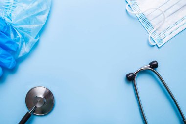 Mavi Arkaplanda Tıbbi Koruma Maskesi ve Mavi Eldiven, tek kullanımlık kep ve steteskop üst görünümü