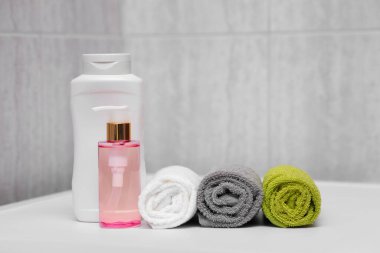 Duş losyonundan sonra üç farklı renk havlu, şampuan ve yağ. Otelde duş hazır..