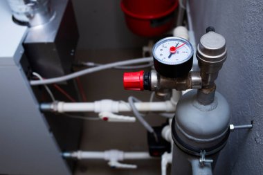 Özel bir evin ısıtma sistemi, manometre, dağıtım manifoldu, gaz teçhizatlı kazan dairesi, su boruları. Gemi konteynırı dağıtılıyor.