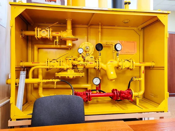 Station for reducing gas pressure in the gas supply system. Educational model of a cabinet-type gas transmission station. Yellow metal box with gas regulator, filters, monometers and vent plugs.