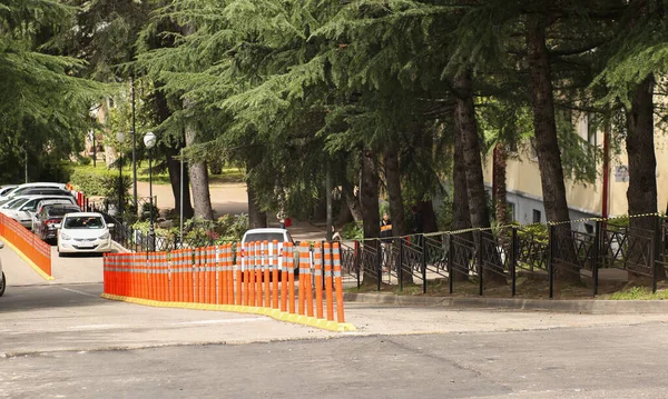 A estrada divide-se por colunas de estrada vermelhas em uma rua de cidade na luz solar. — Fotografia de Stock