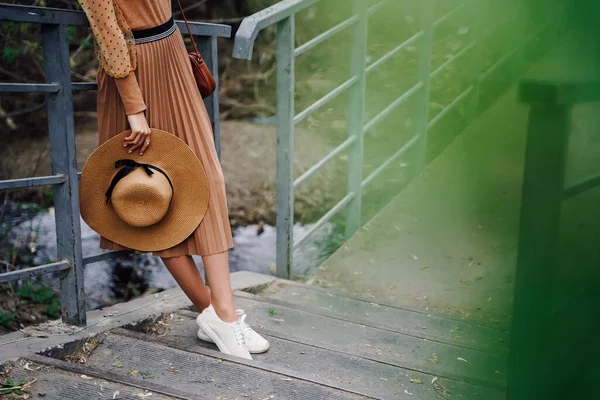 Fashionable female accessories hat and beautiful legs in a skirt. Beige pastel colors are the trend of the season. Fashion and stylish concept.