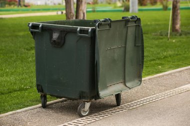 Sokaktaki büyük yeşil plastik çöp konteynırı.
