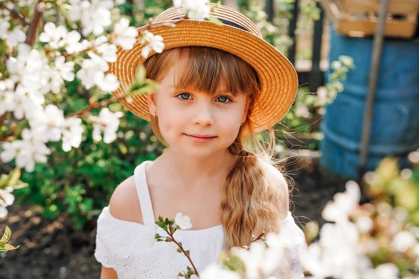 Dívka farmář v klobouku na zahradě se zabývá zahradničení, jarní kvetení meruněk. Rozkvetlá zahrada — Stock fotografie