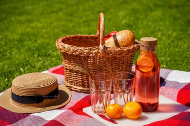 Çimlerin üzerinde piknik, kırmızı bir ekose battaniye, hasır bir sepet, portakal ve böğürtlenlerden yapılmış doğal bir içecek, bir somun ekmek. Yazın dışarıda nefis atıştırmalıklar.