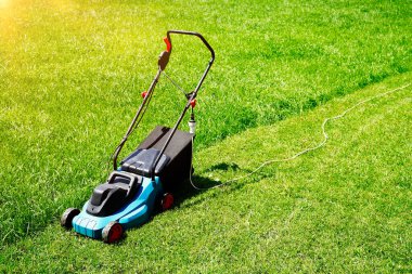 Çim biçme makinesi yemyeşil çimlerde, çimlerin yarısı budanmış. Evin arka bahçesi..