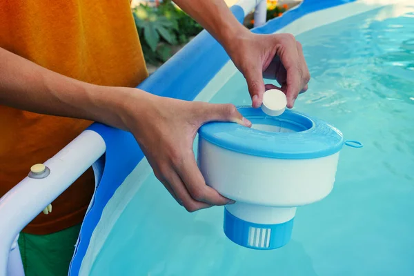 White mini chlorine tablet in the hand of a service worker for disinfection of swimming pools. The beginning of the swimming season is hot summer.