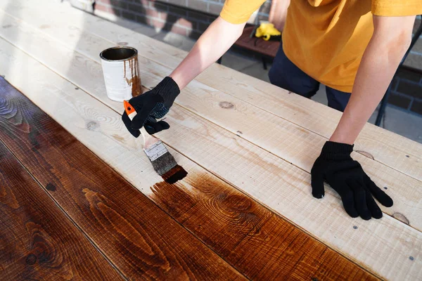 Ręka trzymająca pędzel nakładający lakier na drewnianą powierzchnię — Zdjęcie stockowe