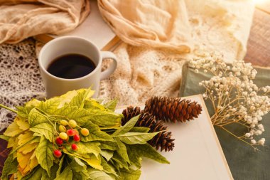 Sonbahar konsepti. Akçaağaç yapraklı çay fincanı ve kitaplar. Güzel bir sonbahar kompozisyonu. Kırsal ahşap arka planda çay fincanı.