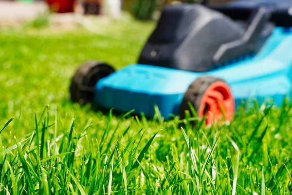 Wazig grasmaaier elektrische machine trimmen en richten op groen gras. Grasmaaien — Stockfoto