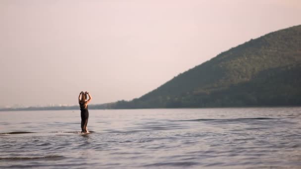 Fille par la rivière dans une robe noire vient dans l'eau sur le fond des montagnes — Video