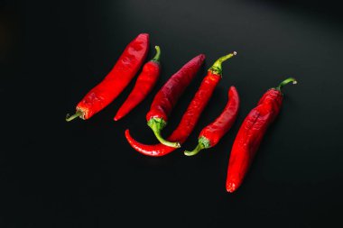 Kırmızı renkte taze kırmızı biberler siyah arkaplanda eşit olarak dizilmiş..