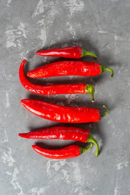 Taze kırmızı biberler, çimento arka planda eşit olarak serili..