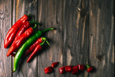 Kırmızı ve yeşil renkli taze kırmızı biberler eskimiş bir ahşabın arka planına eşit olarak yayılmış. kopyalama alanı
