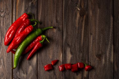 Kırmızı ve yeşil renkli taze kırmızı biberler eskimiş bir ahşabın arka planına eşit olarak yayılmış. kopyalama alanı