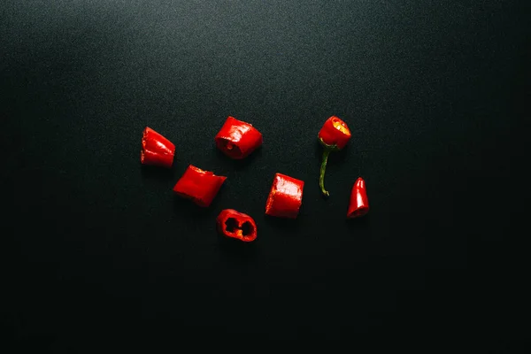 Taze Kırmızı Biber Parçalara Ayrılmış Siyah Arka Planda Uzanmış — Stok fotoğraf