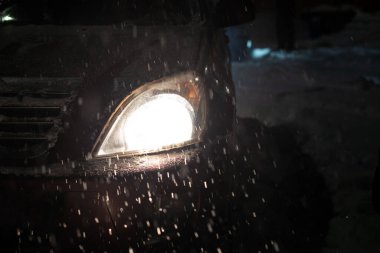 Şiddetli bir kar yağışı sırasında arabanın parlayan farlarının arkasına kar yağıyor. Kar fırtınası.