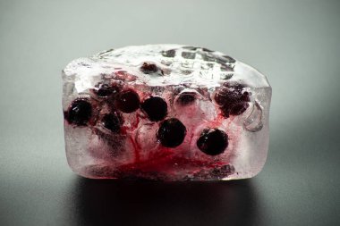 Siyah arka planda buzun içinde donmuş kara frenk üzümü..