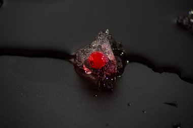 Siyah arkaplanda bir parça buzlu üzümlü kuşüzümü. Eriyen buz briketine yakın plan