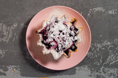 Pembe bir fincan tabağında çilek ve süzme peynirli kek sepeti. Taze çilek ve süzme peynirli büyük tart, üzerine pudra şekeri serpiştirilmiş. Düz beton arkaplan