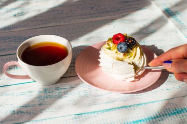 Krem şantili ve taze dutlu Pavlova kremalı pasta. Bir kupa taze kahve. Beyaz ve mavi masa.