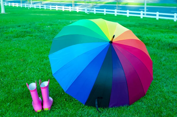 Rainbow umbrella with boots on the grass