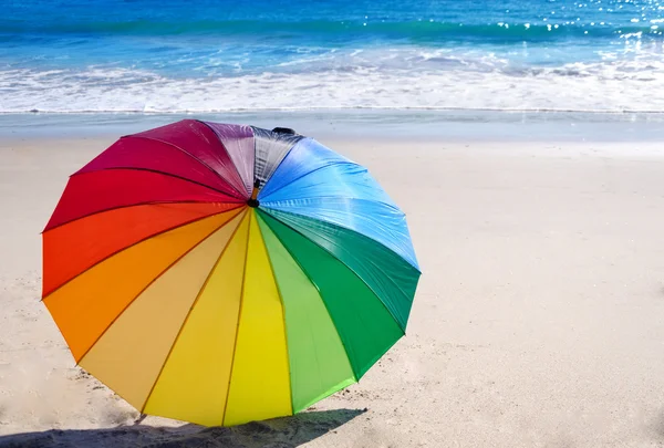 Rainbow umbrella by the ocean — Stock Photo, Image