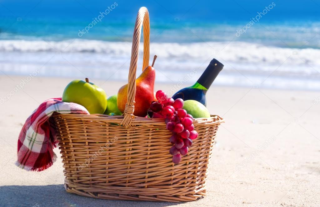 Picnic basket with fruits by the ocean