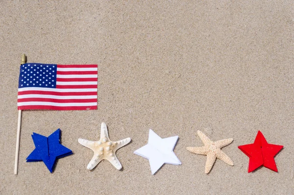 Bandiera amricana con stelle marine sulla spiaggia di sabbia — Foto Stock