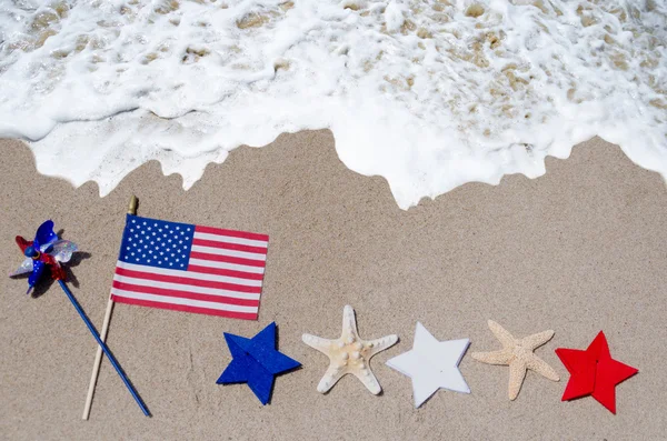 Americká vlajka s starfishes na písečné pláži — Stock fotografie