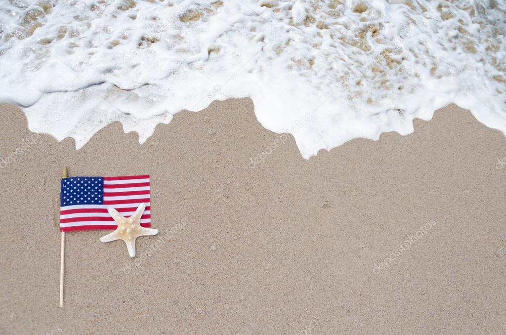 American flag with starfish on the sandy beach Stock Photo by