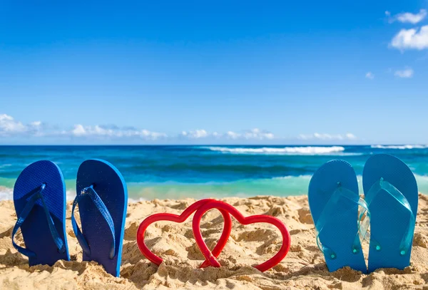 Flip flops with heart shapes on the sandy beach — Stockfoto