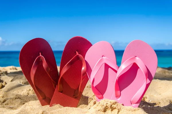 Infradito rosse e rosa sulla spiaggia di sabbia — Foto Stock
